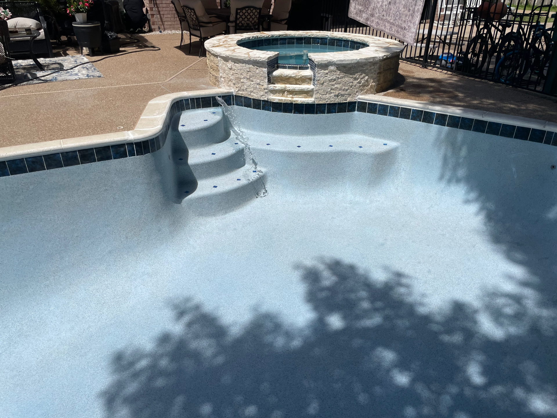 Geometric pool with raised spa, spillway, and light blue pebble finish