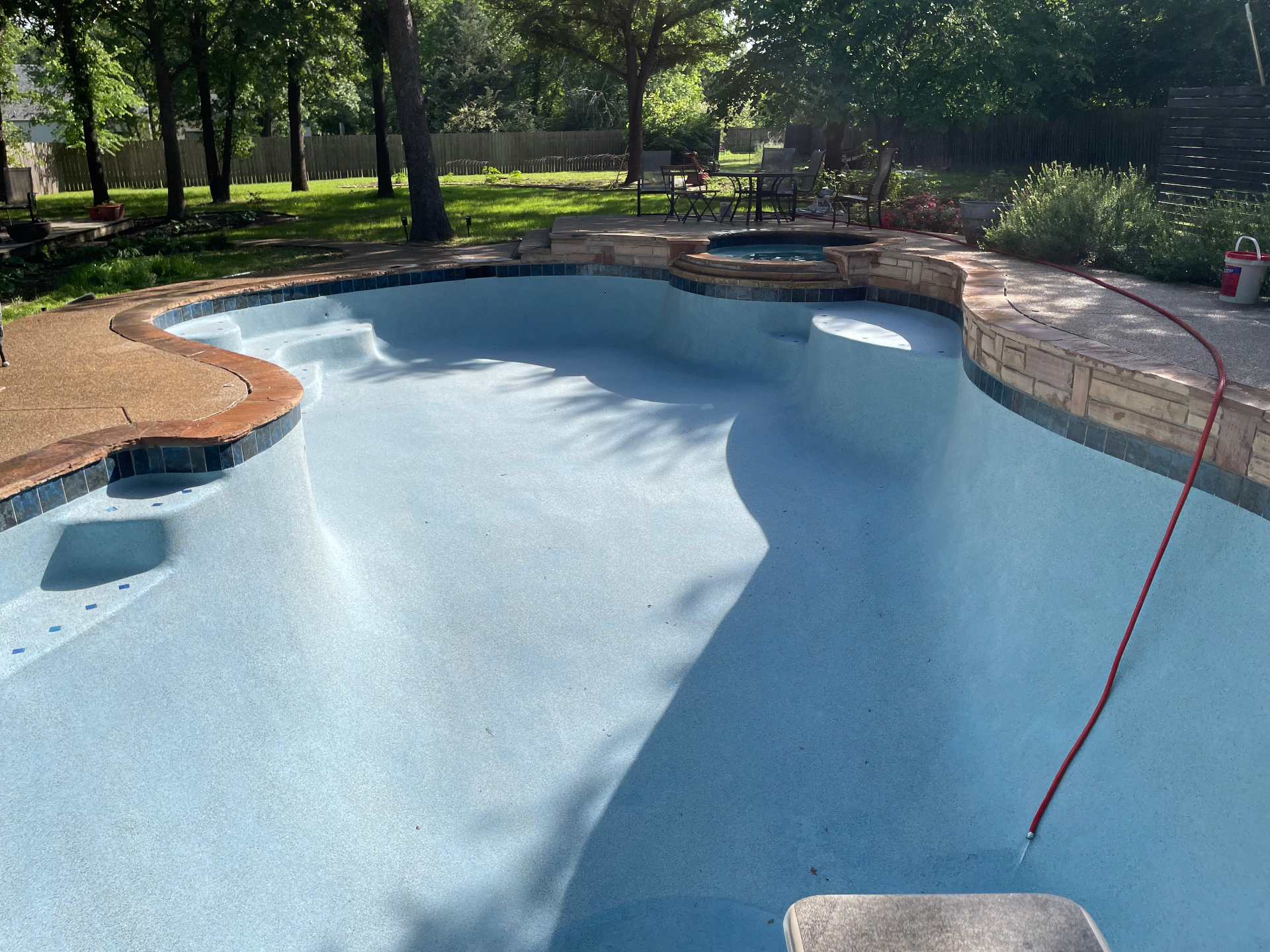 Freeform pool and raised spa with flagstone coping and blue waterline tile after resurfacing