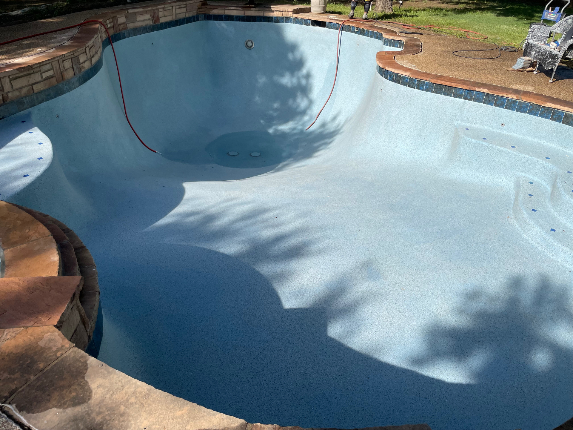 Deep end of freeform pool showing fresh light blue pebble finish and stone coping