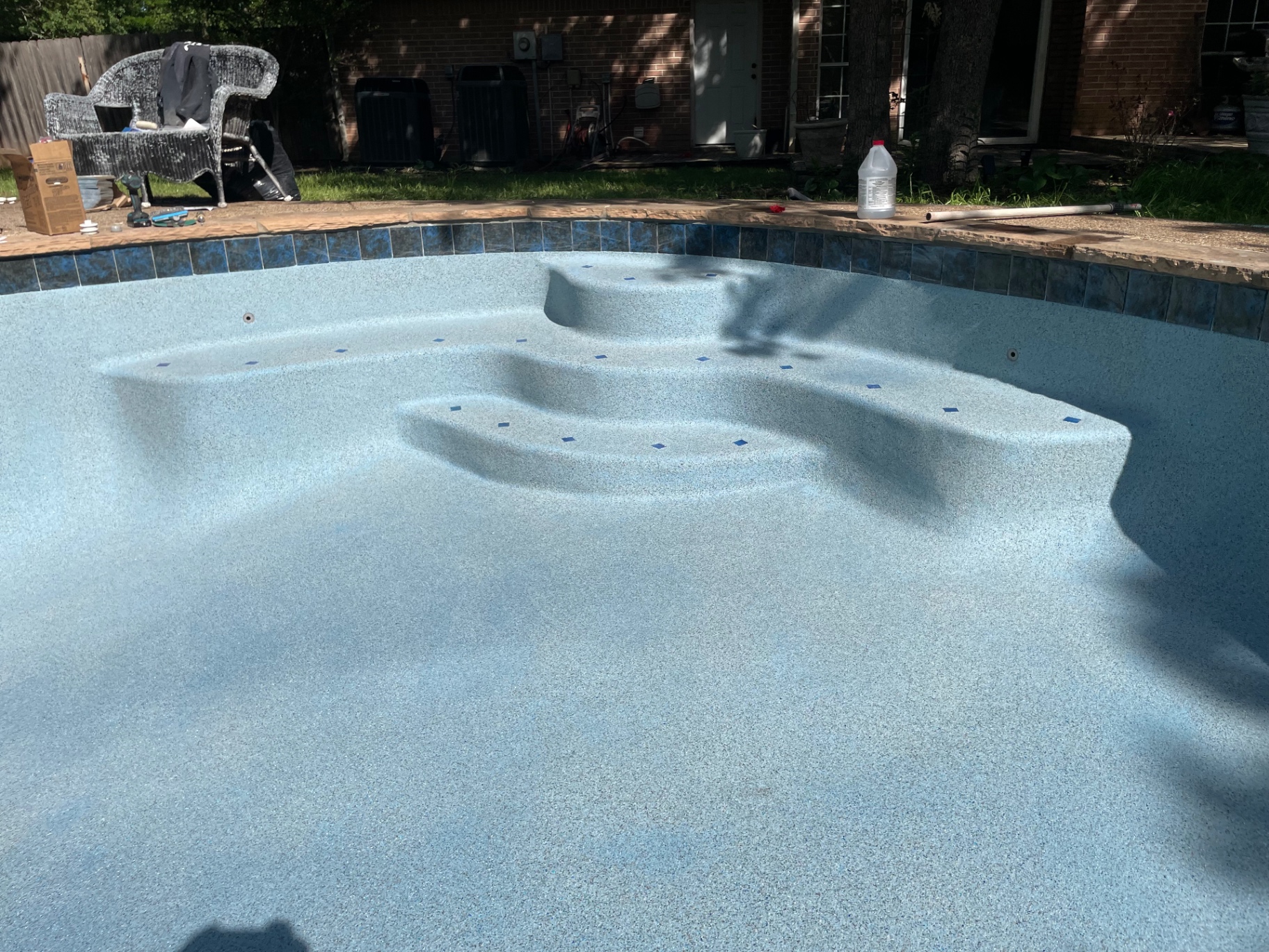 Pool tanning ledge and entry steps with blue glass waterline tile accents