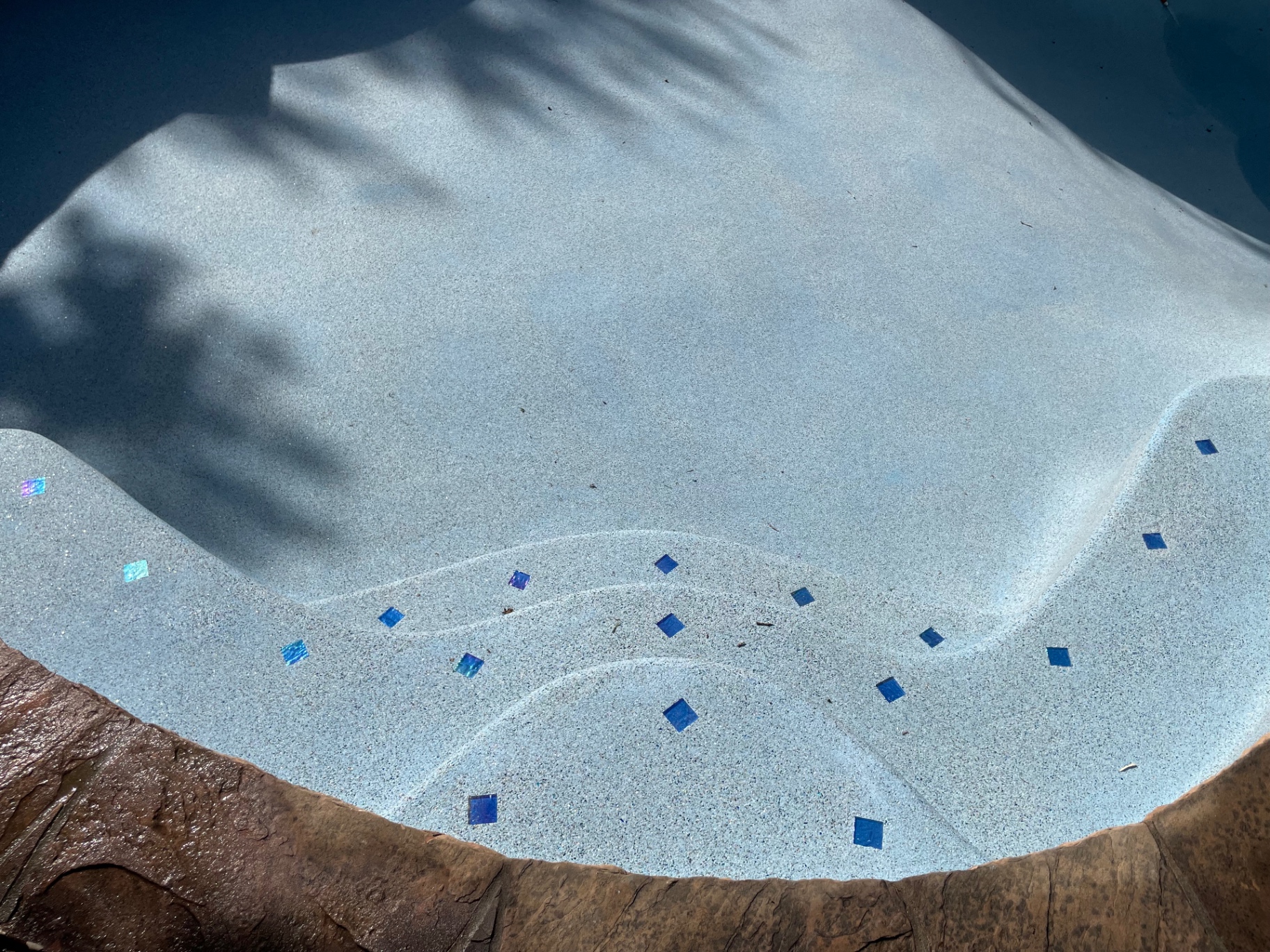Close-up of pool tanning ledge with iridescent and cobalt blue glass tile accents