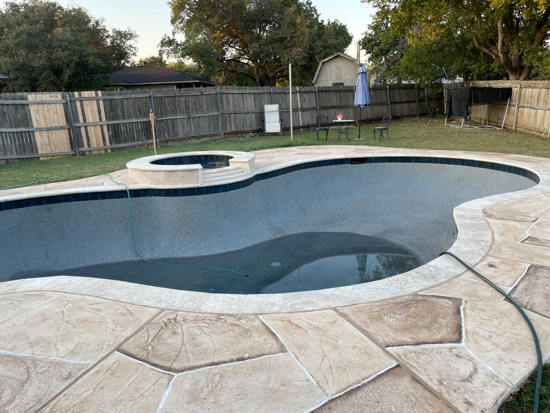 Freeform pool with raised spa, flagstone decking, and dark pebble finish
