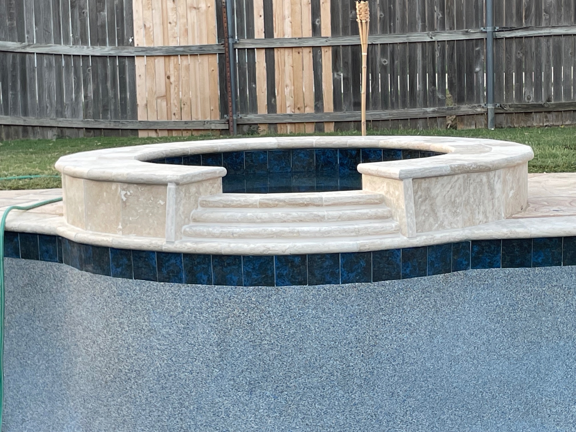 Travertine raised spa with deep blue waterline tile