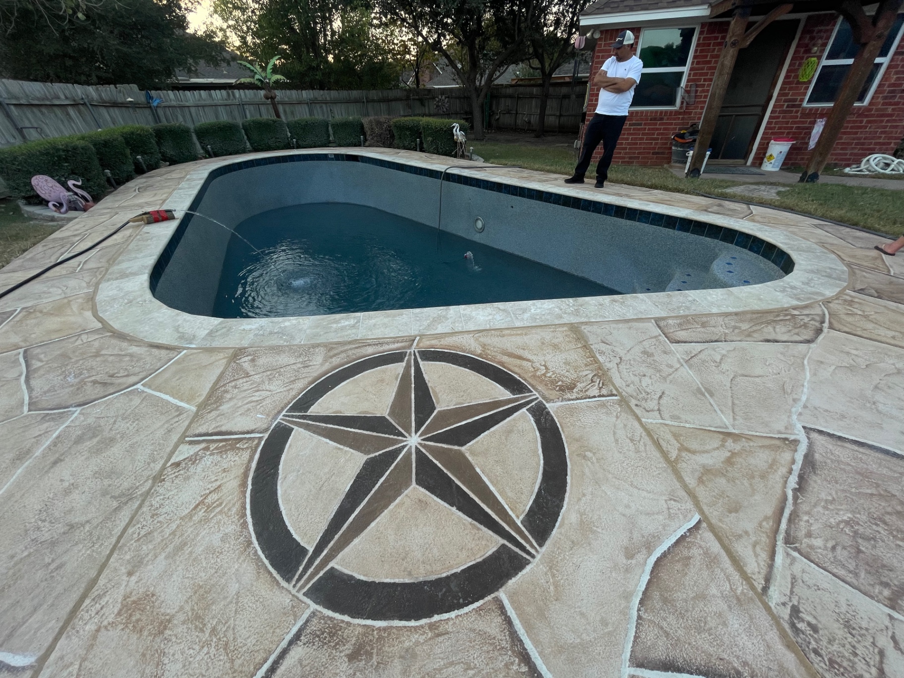 Roman-style pool with dark pebble finish and Texas star flagstone deck