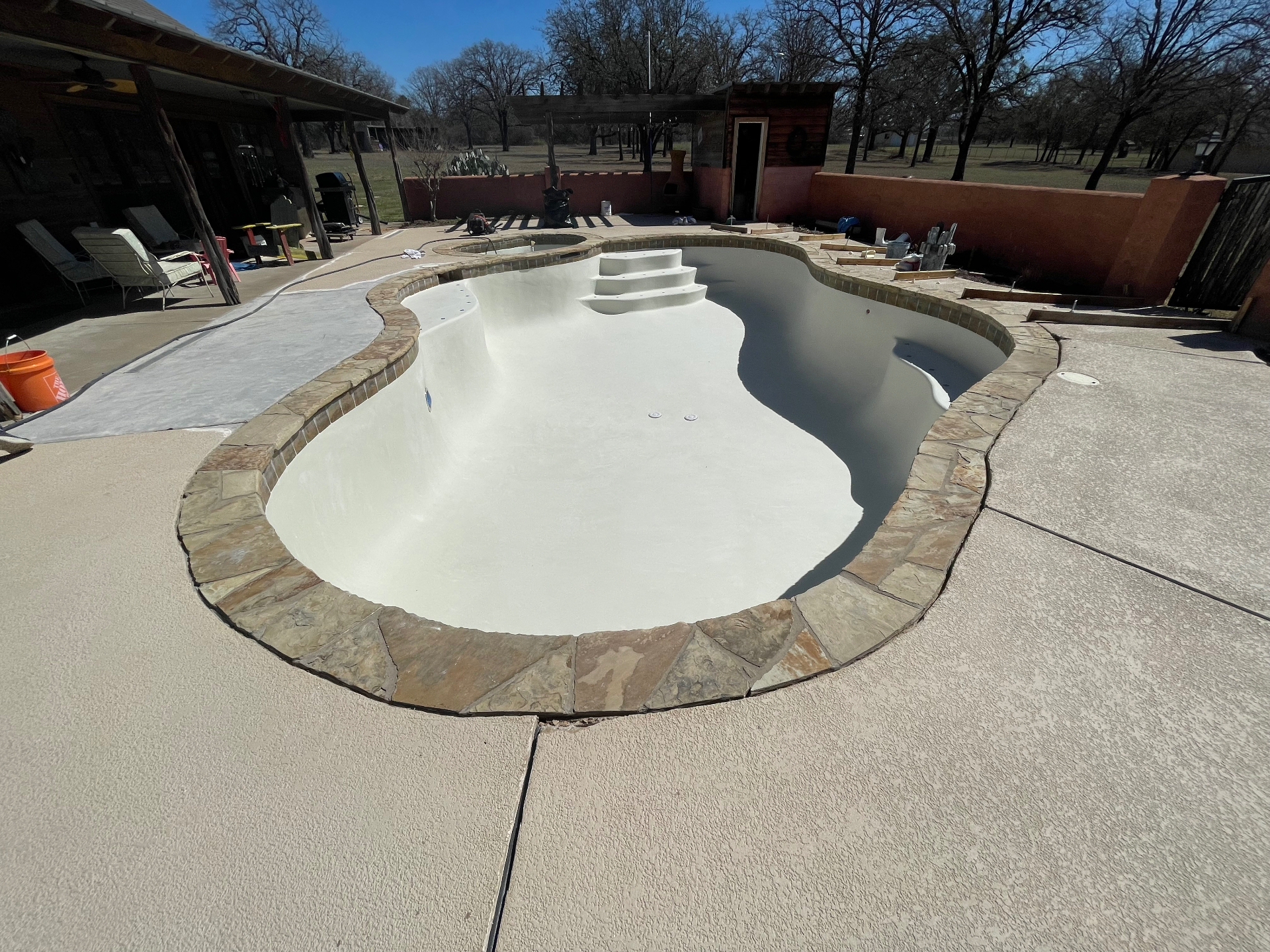 Freshly plastered freeform pool with flagstone coping ready for fill