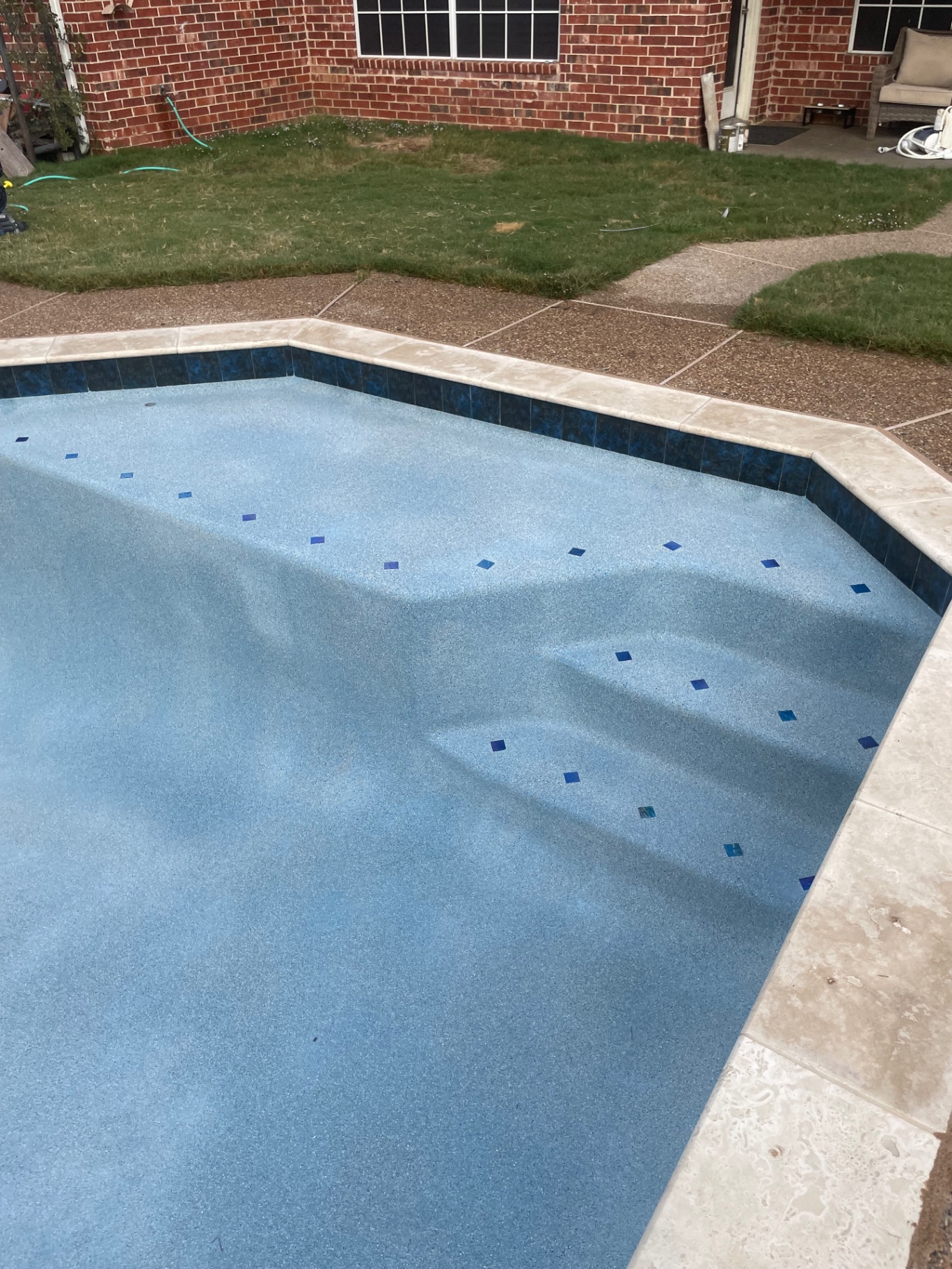 Geometric pool with blue pebble finish and cobalt glass tile accents along bench seating